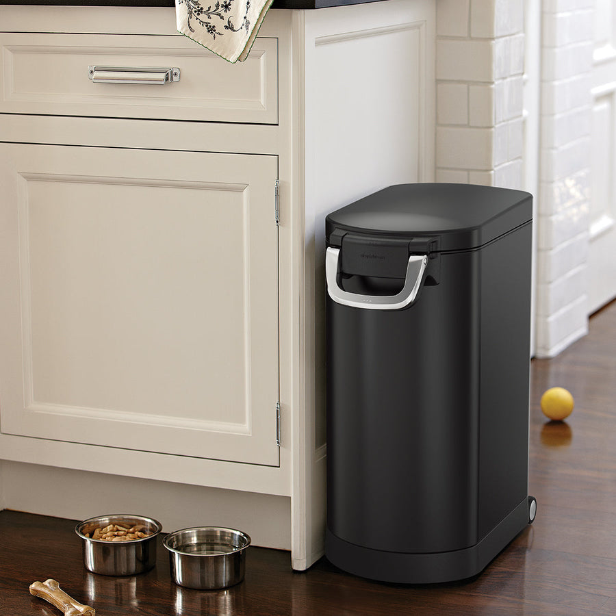 Angled view of Simplehuman Matte Black Large Pet Food Can, closed securely in kitchen setting, airtight locking handle.
