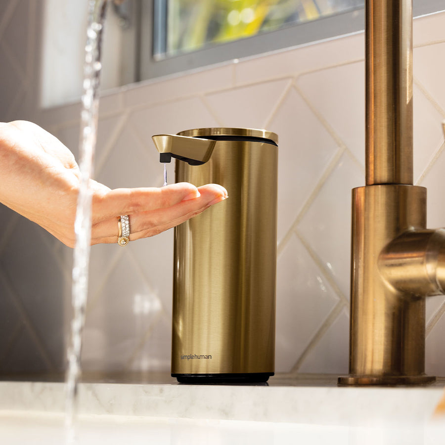 Angled view of Simplehuman Brass Sensor Pump dispensing Geranium soap, touch-free operation.