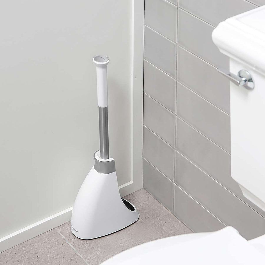 Lifestyle view of Simplehuman Toilet Brush (White/Stainless Steel) positioned discreetly in a bathroom corner, space-saving design.