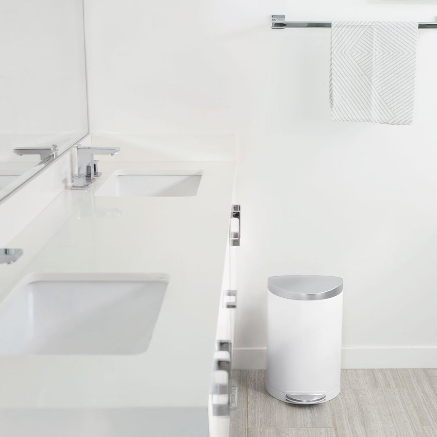 Lifestyle view of Simplehuman 10L Semi-Round Step Can, White, in modern bathroom setting, hands-free foot pedal.